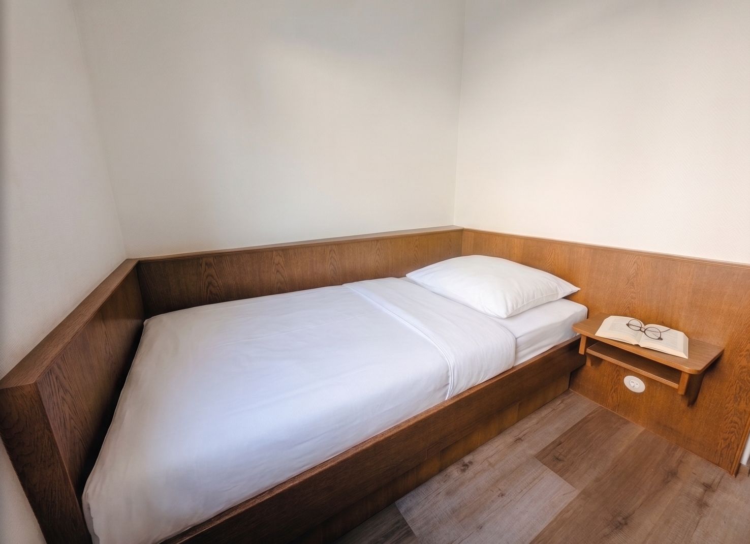 Einzelbett mit Holzrahmen in einer ruhigen Ecke des Zimmers