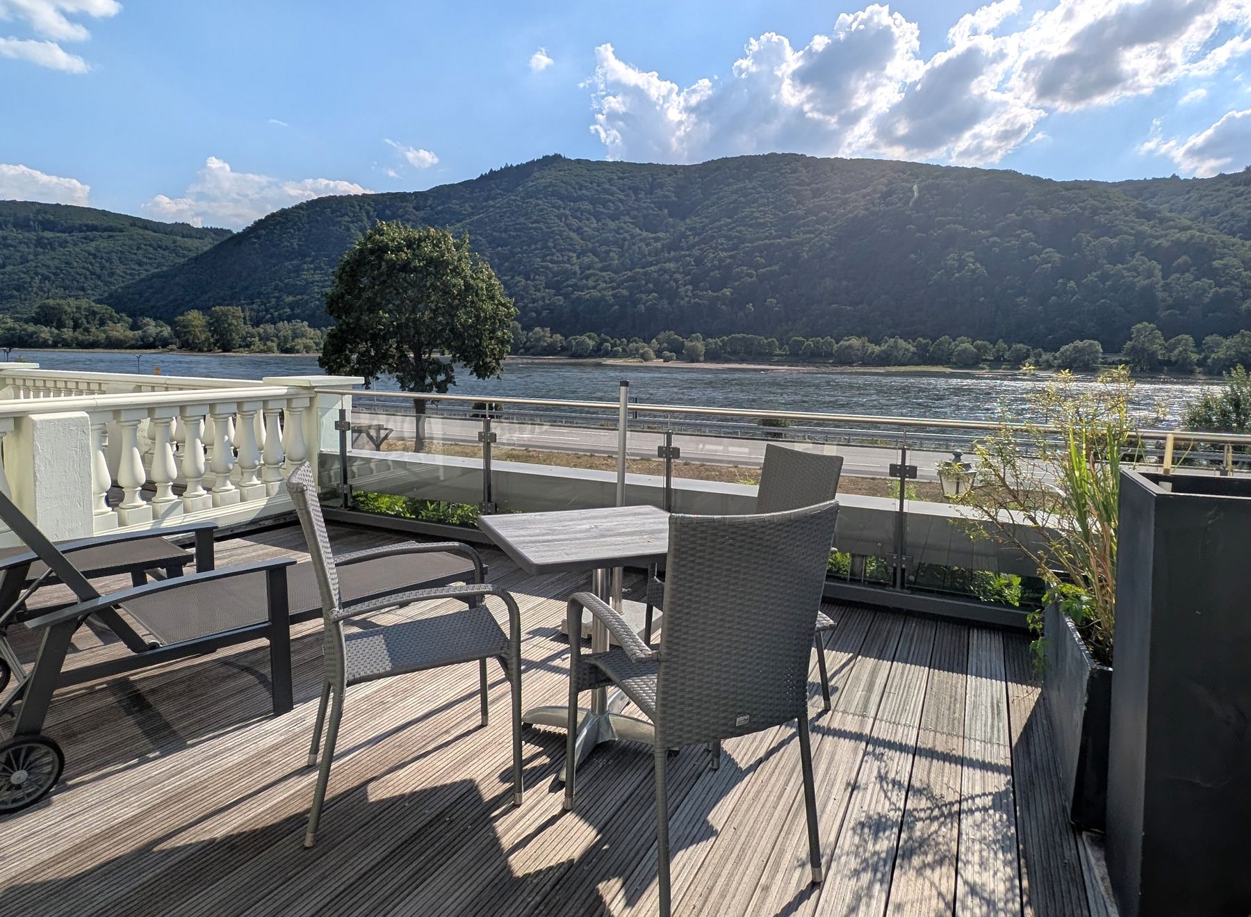 Großer Balkon mit Holzboden, Sonnenliege, Tisch und Stühlen über dem Rhein
