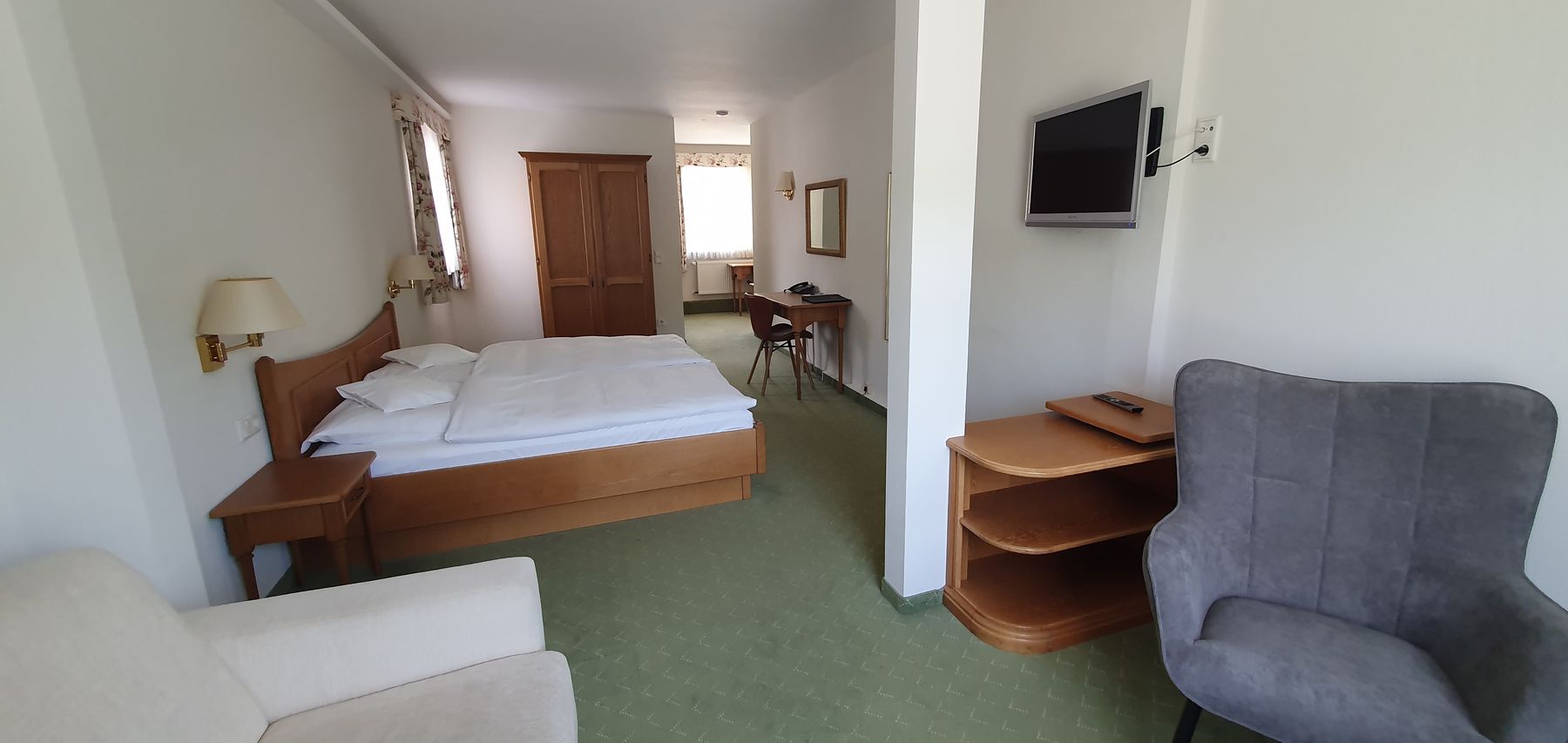Blick in den Schlafbereich mit Doppelbett, im Vordergrund ein Sessel