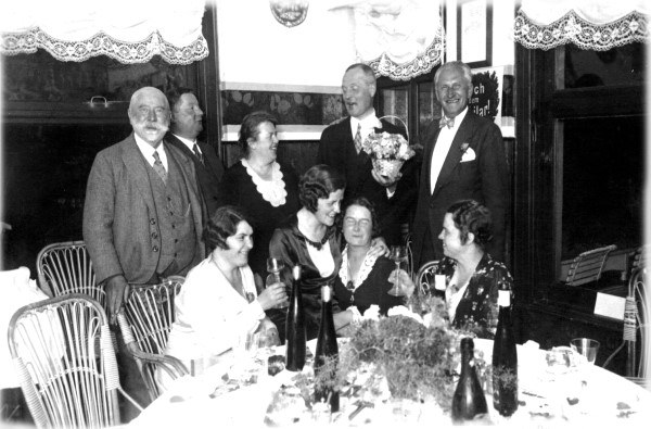 Eine festlich gekleidete Gesellschaft an einer gedeckten Tafel im Hotel