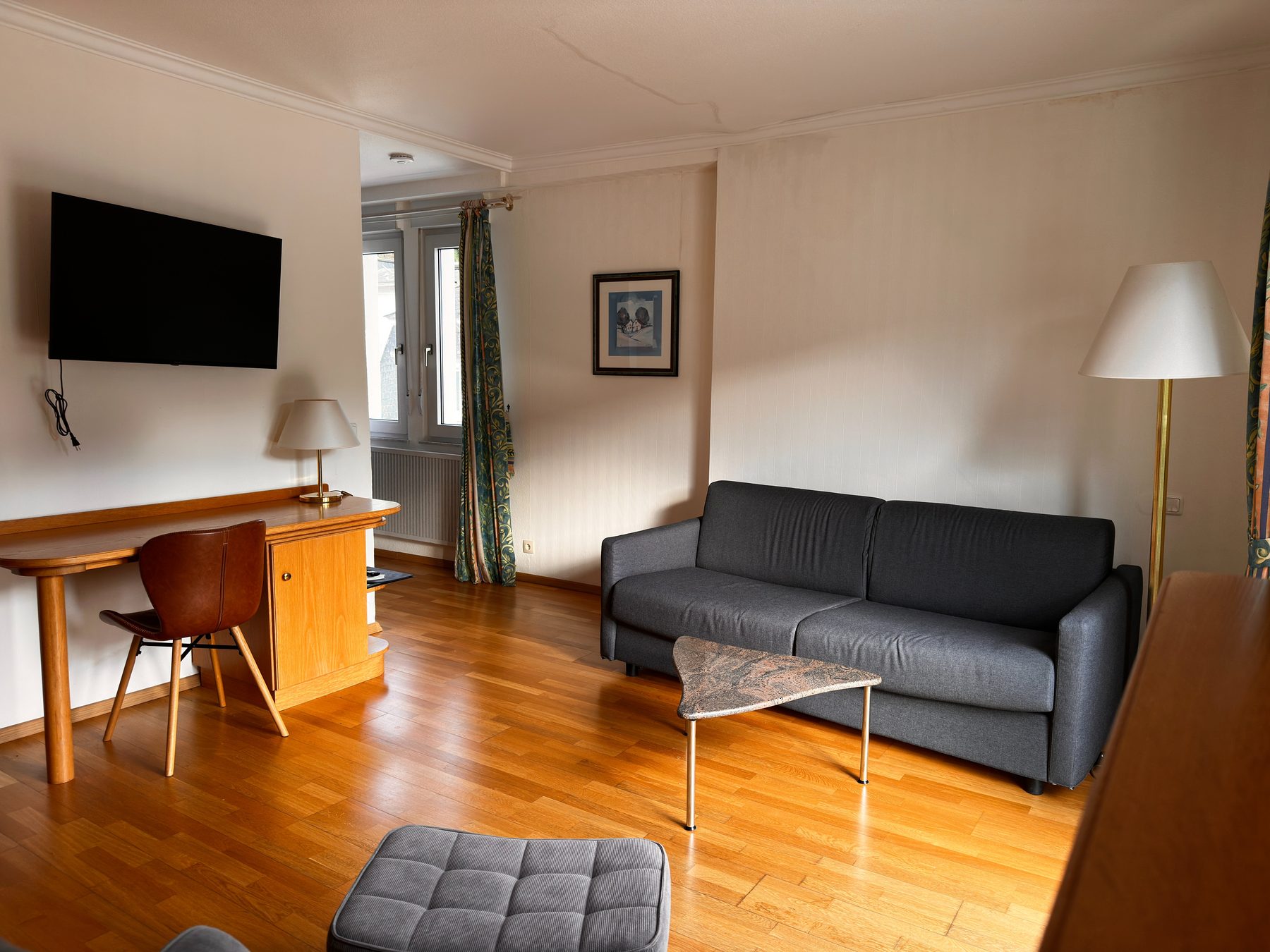 Wohnbereich mit Schreibtisch, Fernseher, Sofa und Parkettboden
