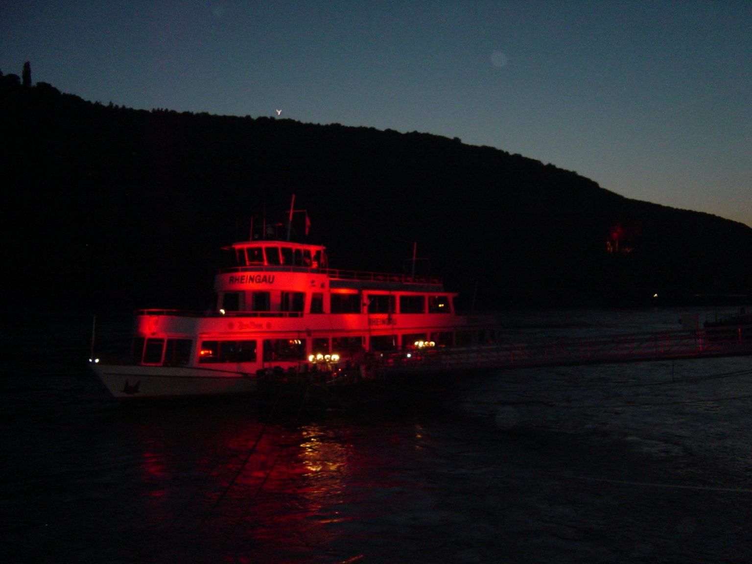 The Rössler Linie's Rheingau in the evening, lit up in red at the landing stage